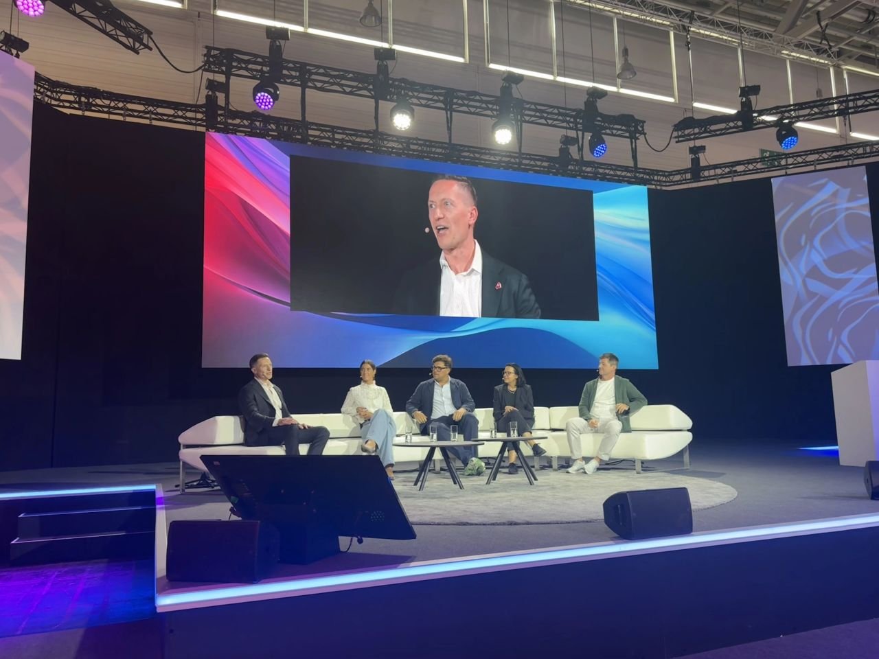 Evgeny Popov on the big screen above the DMEXCO 2026 Tech Stage, moderating the From Data to Impact panel with four panelists seated on stage